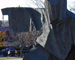 Photo of two runners and the Law School tai chi statue at the KU Veteran's Day 5K.